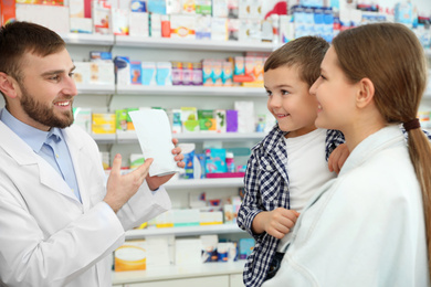 Image of Professional pharmacist working with customer in modern drugstore