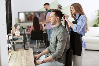 Photo of Professional hairdresser working with client in beauty salon