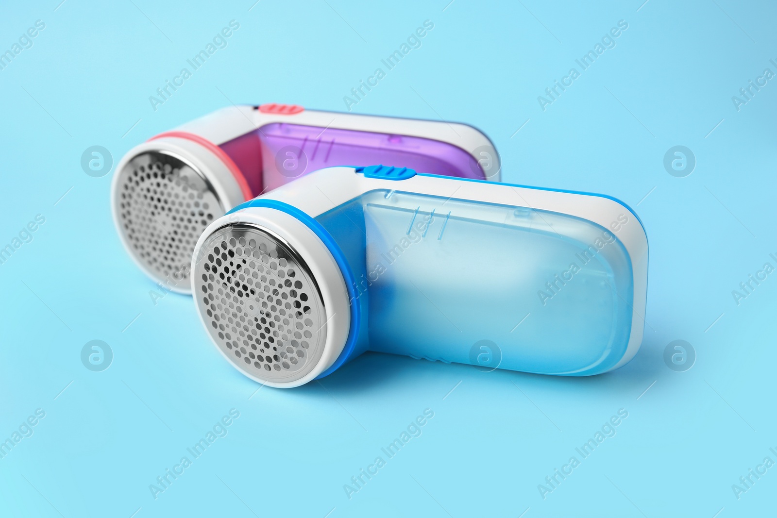 Photo of Modern fabric shavers on light blue background