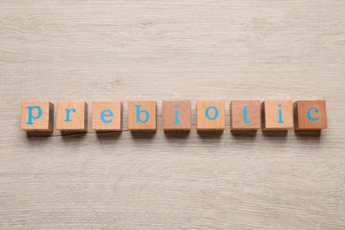 Photo of Word Prebiotic made of cubes with letters on wooden table, top view