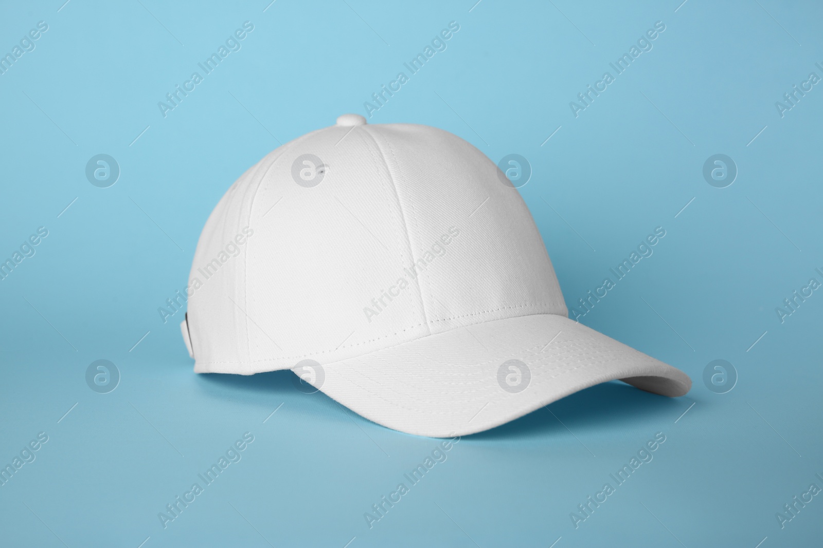 Photo of Stylish white baseball cap on light blue background