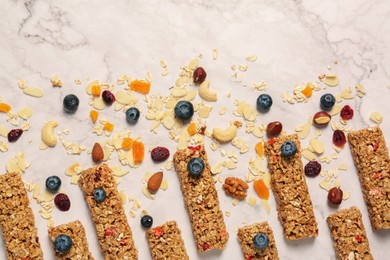 Tasty granola bars and ingredients on white marble table, flat lay