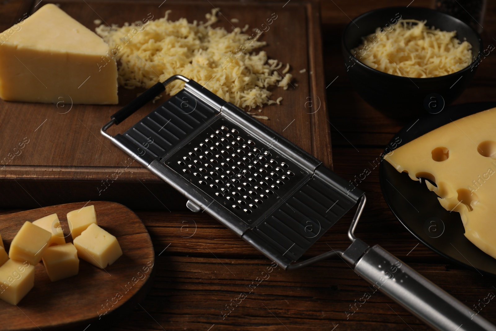 Photo of Different types of cheese and grater on wooden table, closeup