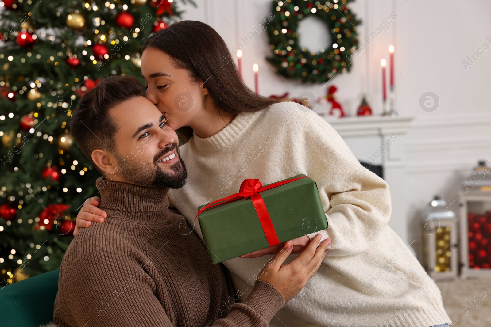 Photo of Beautiful young couple with Christmas gift at home