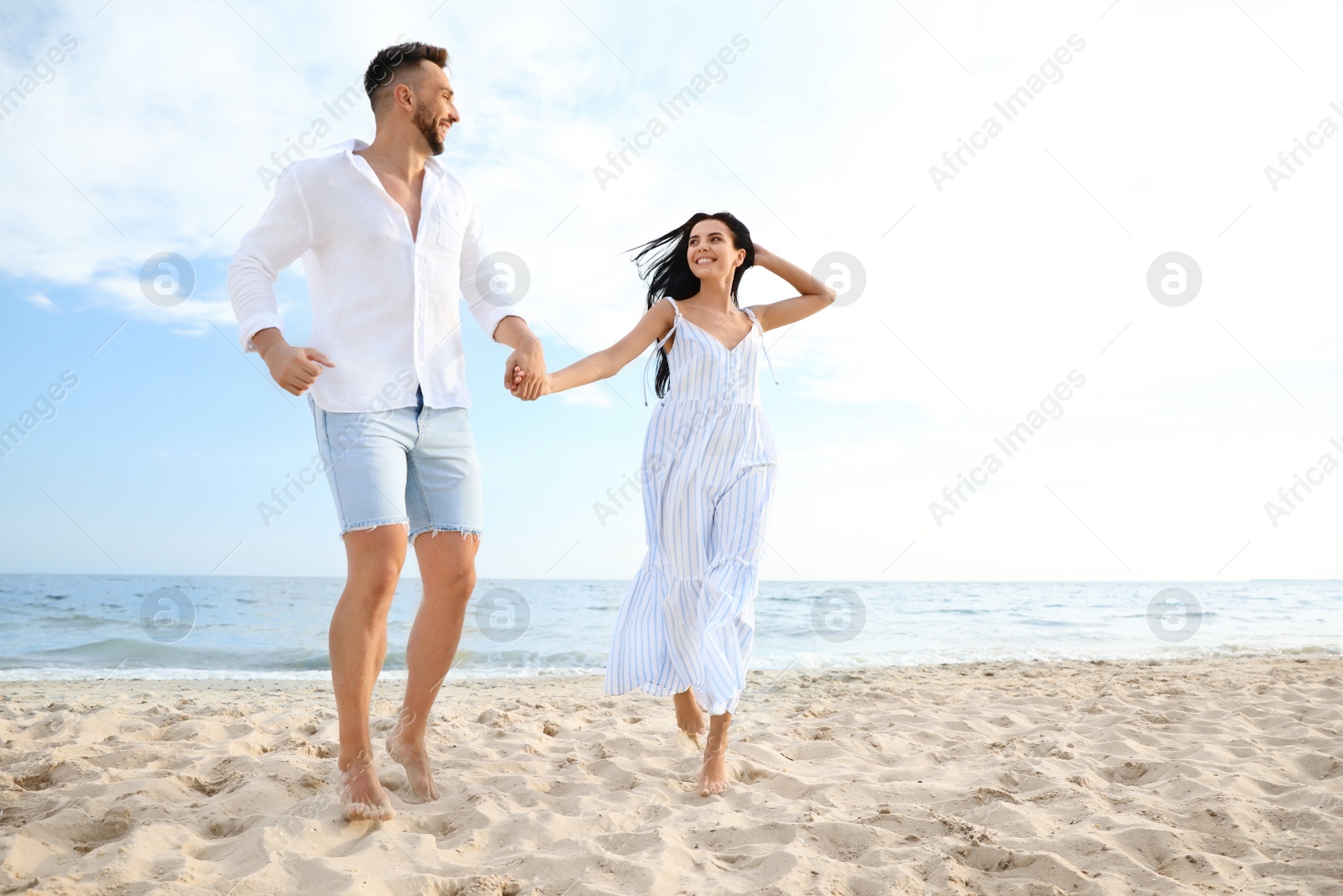 Photo of Happy young couple running together on beach