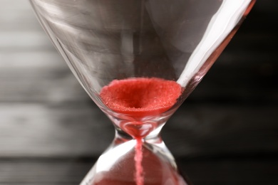 Hourglass with flowing sand on table, closeup. Time management