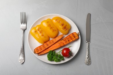 Photo of Delicious grilled vegetables served on grey table, flat lay