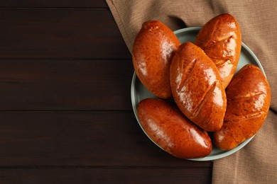 Photo of Delicious baked pirozhki on wooden table, top view. Space for text