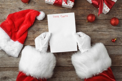 Photo of Santa Claus reading letter from child at table, top view. Christmas celebration