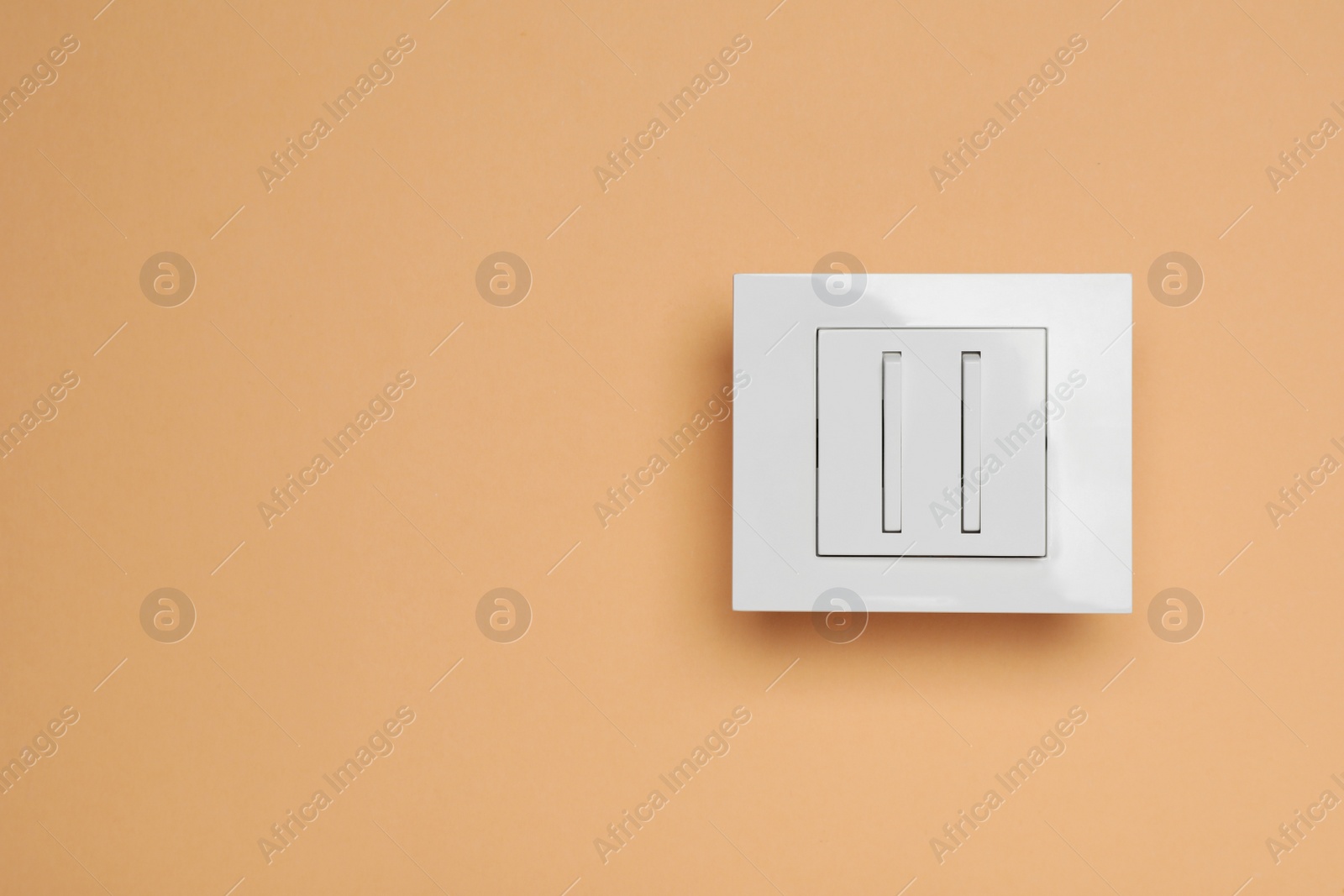 Photo of White light switch on orange background, top view. Space for text