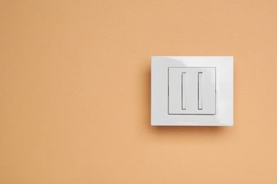 Photo of White light switch on orange background, top view. Space for text