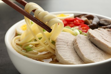 Noodle soup. Eating delicious ramen with chopsticks at table, closeup