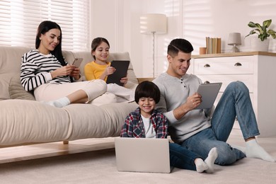 Photo of Internet addiction. Family with different gadgets in living room