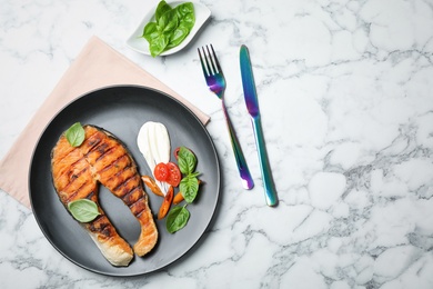 Plate with tasty salmon steak on light background