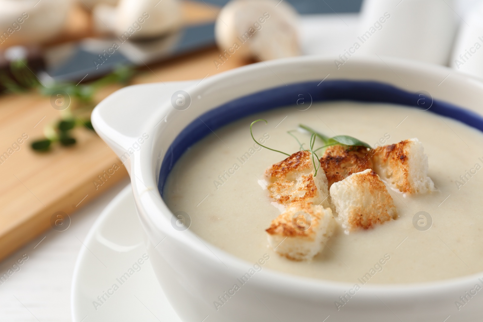 Photo of Delicious cream soup with croutons in bowl on table, closeup