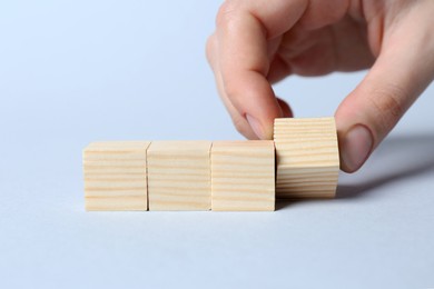 Photo of Woman arranging cubes on light background, closeup with space for text. Idea concept