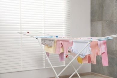 Photo of Clean laundry hanging on drying rack indoors