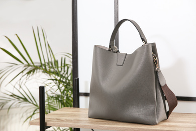 Photo of Grey woman's bag on wooden shelf in store