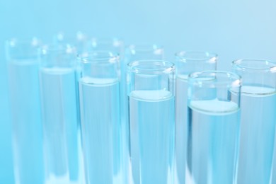 Photo of Laboratory analysis. Test tubes with liquid samples on light blue background, closeup