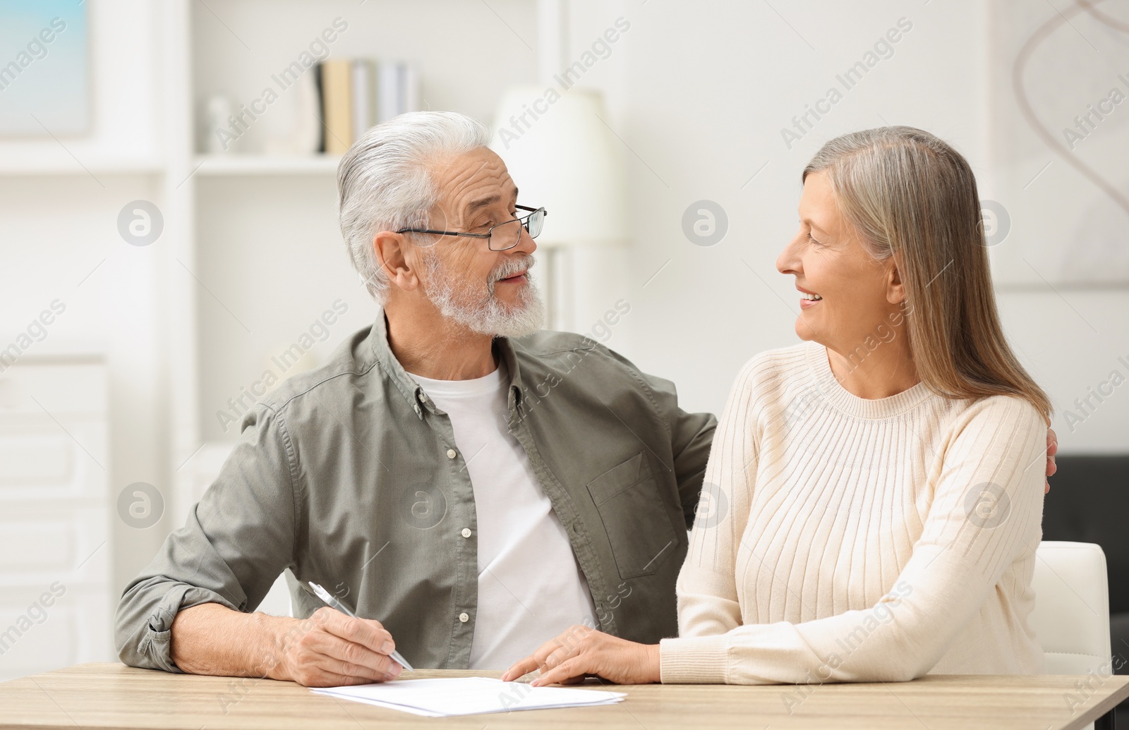 Photo of Senior couple signing Last Will and Testament indoors