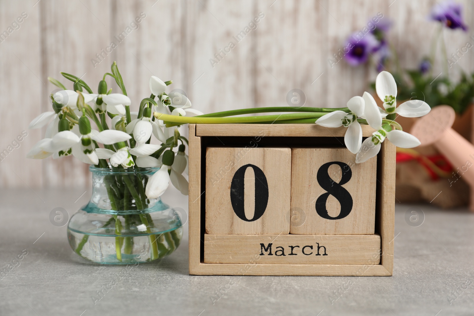 Photo of Women's day greeting card. Block calendar and beautiful snowdrops on grey table