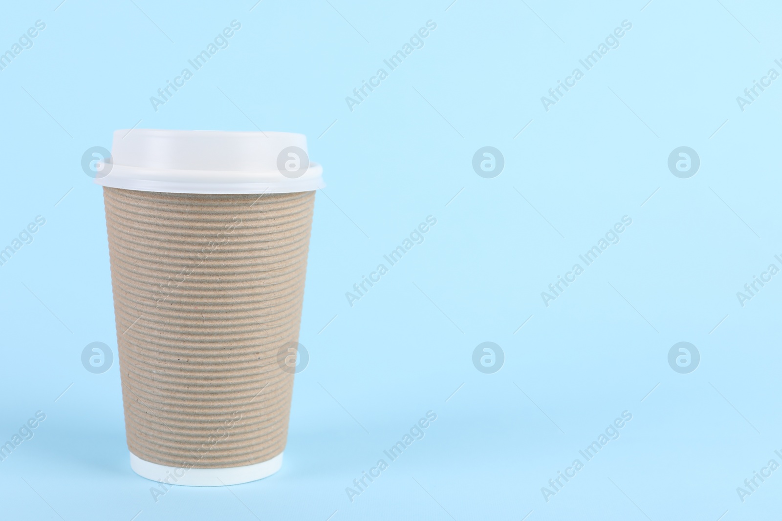 Photo of Paper cup with plastic lid on light blue background, space for text. Coffee to go