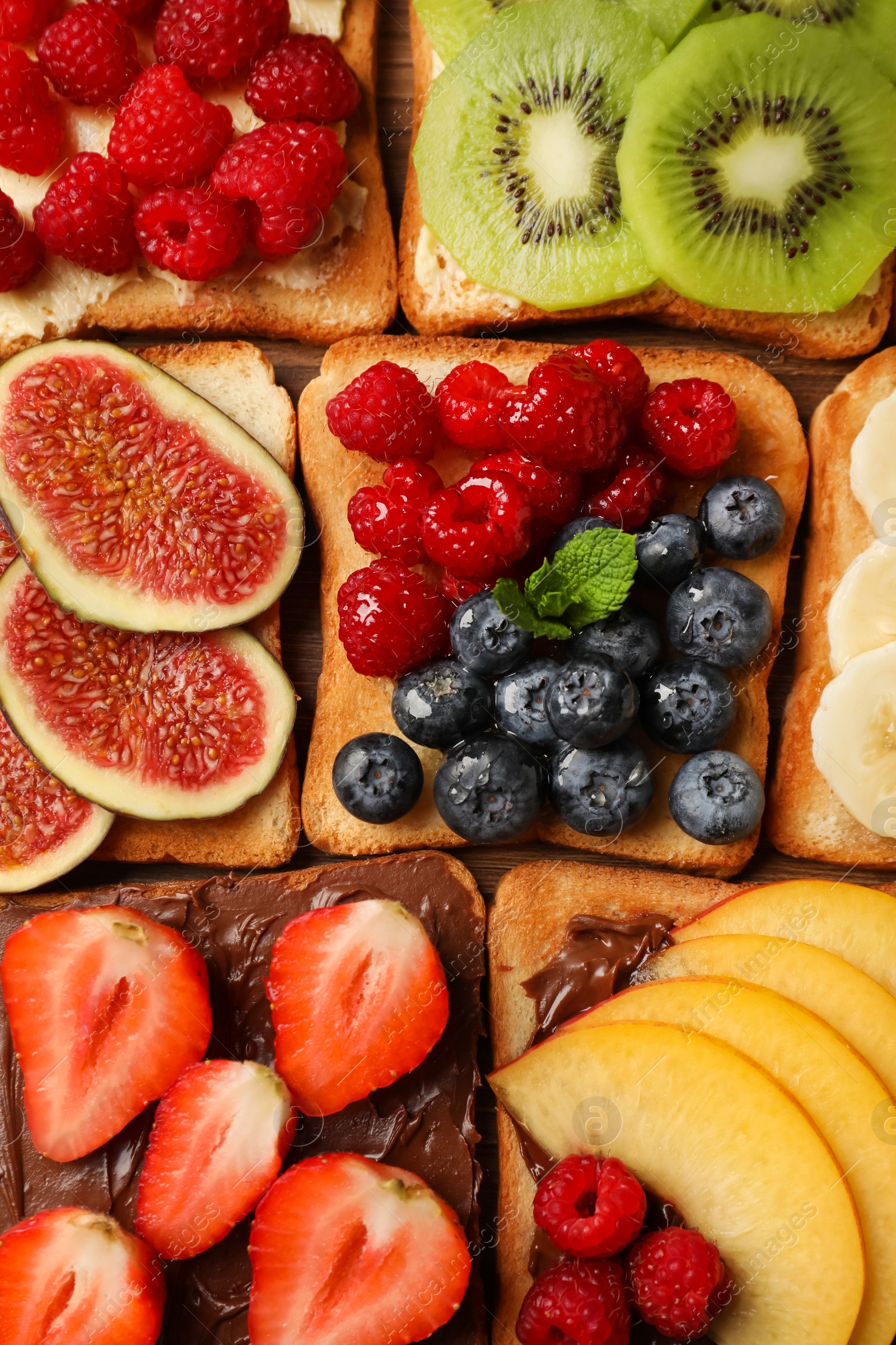 Photo of Tasty toasts with different spreads and fruits on wooden table, flat lay