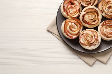 Freshly baked apple roses on white wooden table, top view. Space for text