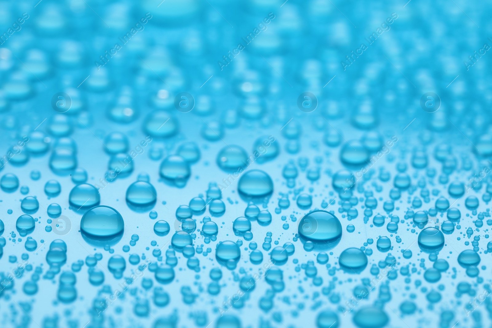 Photo of Water drops on light blue background, closeup view