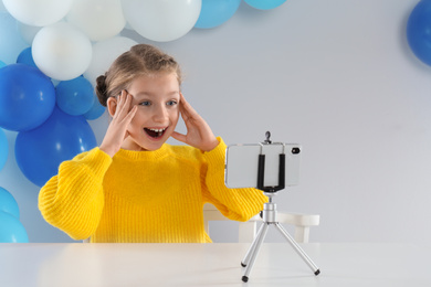 Photo of Excited little blogger recording video at table