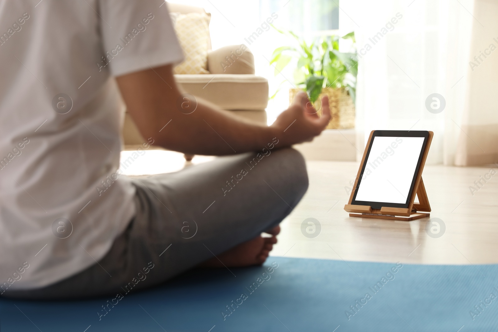 Photo of Man practicing yoga while watching online class at home during coronavirus pandemic, closeup. Social distancing