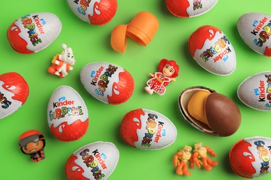 Sveti Vlas, Bulgaria - June 26, 2023: Kinder Surprise Eggs, plastic containers and toys on light green background, flat lay