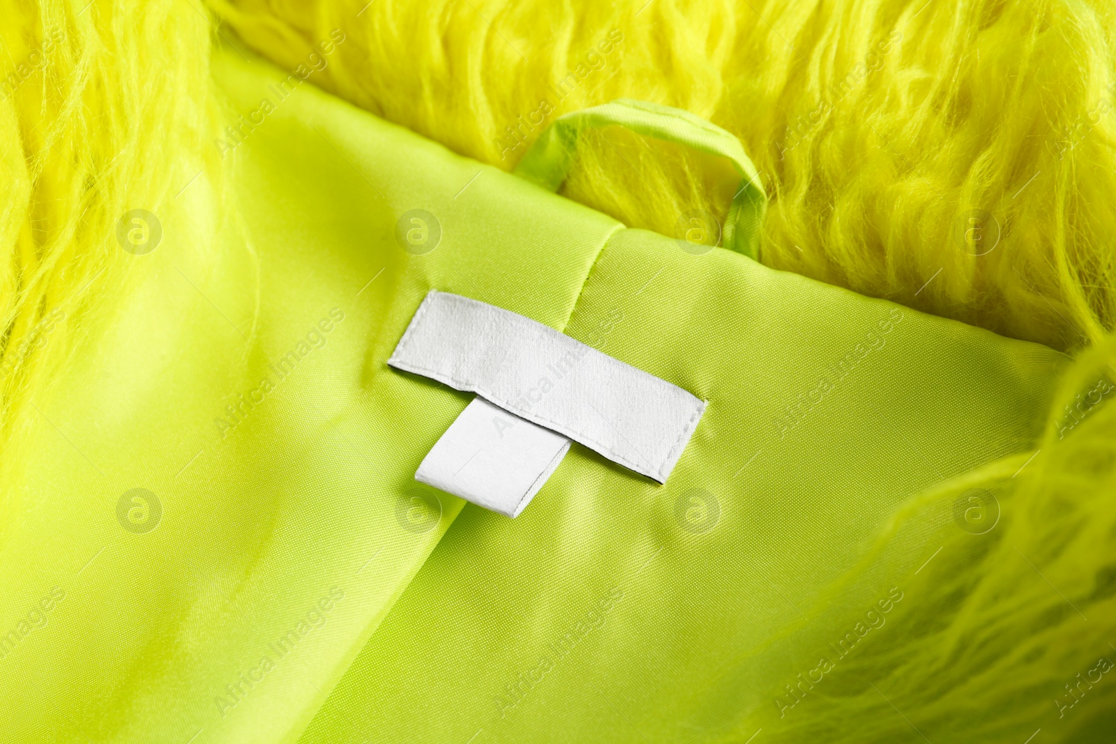 Photo of Blank clothing label on light green jacket, closeup