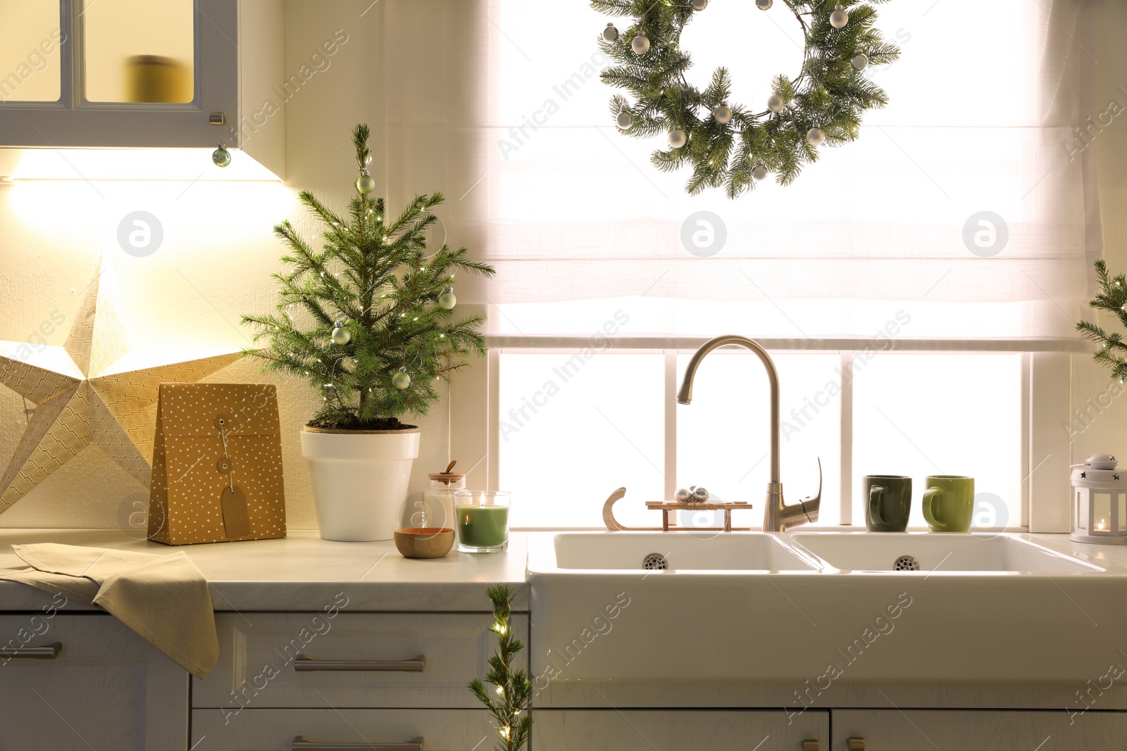 Photo of Small Christmas tree and festive decor on countertop in kitchen