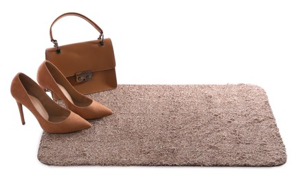 Stylish door mat with high heeled shoes and bag on white background