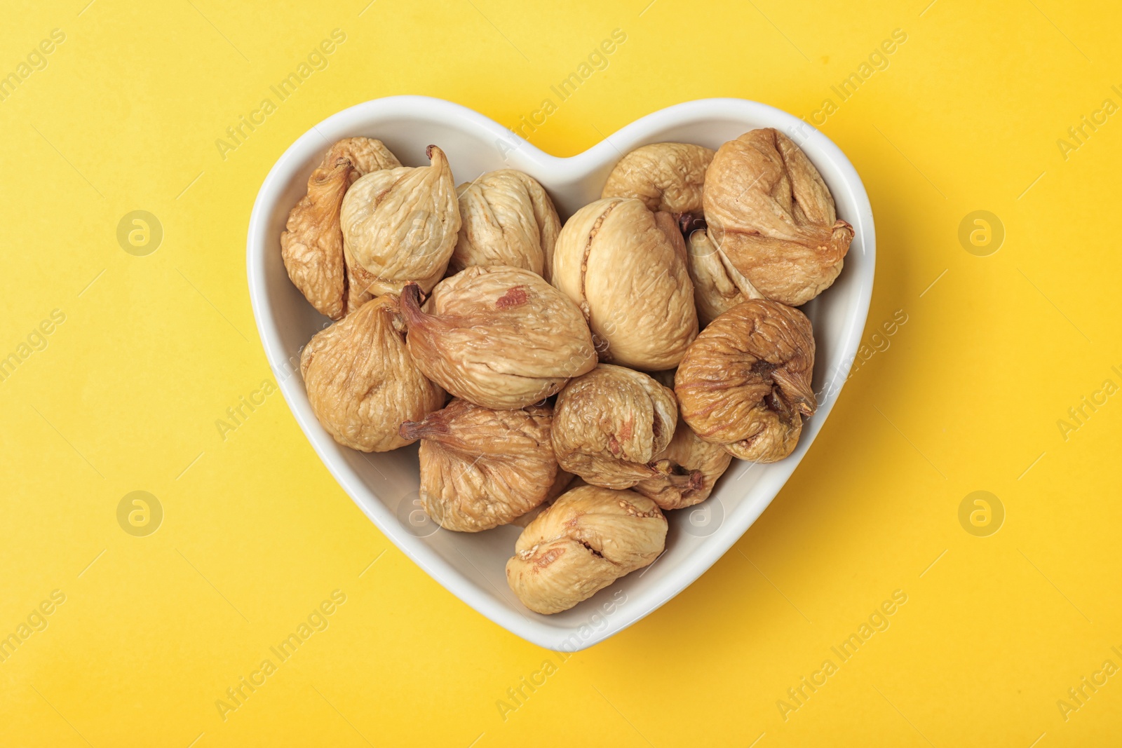 Photo of Bowl with dried figs on color background, top view. Healthy fruit