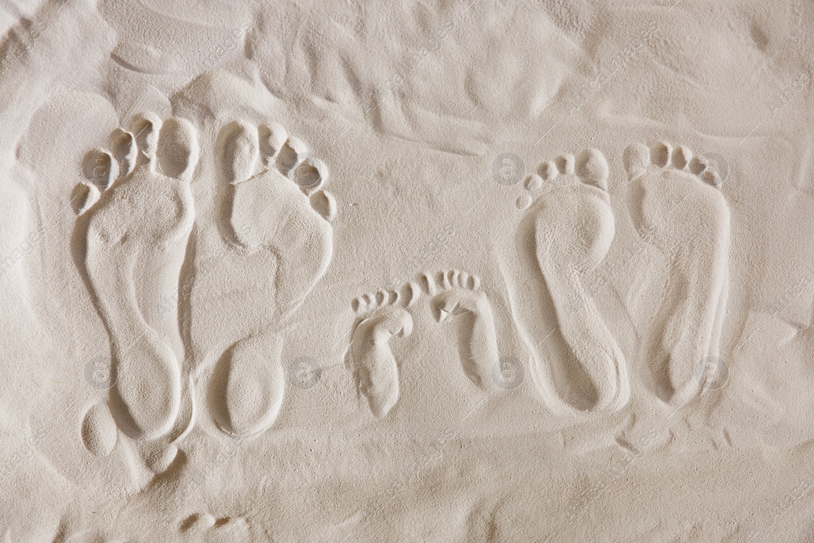 Photo of Family footprints on sandy beach, top view