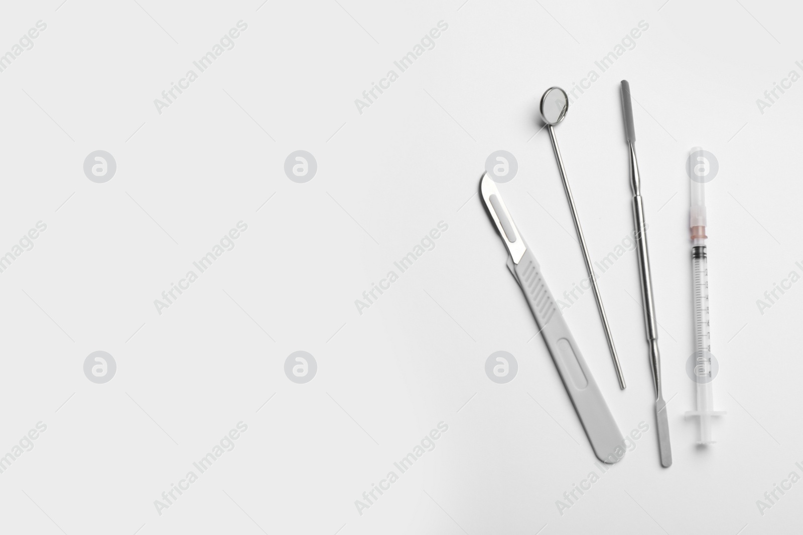 Photo of Set of different dentist's tools and syringe on light background, flat lay. Space for text