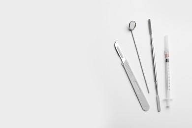 Set of different dentist's tools and syringe on light background, flat lay. Space for text