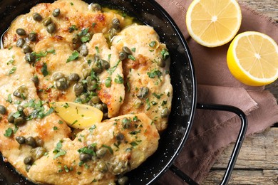 Photo of Delicious chicken piccata with herbs and lemon on wooden table, top view