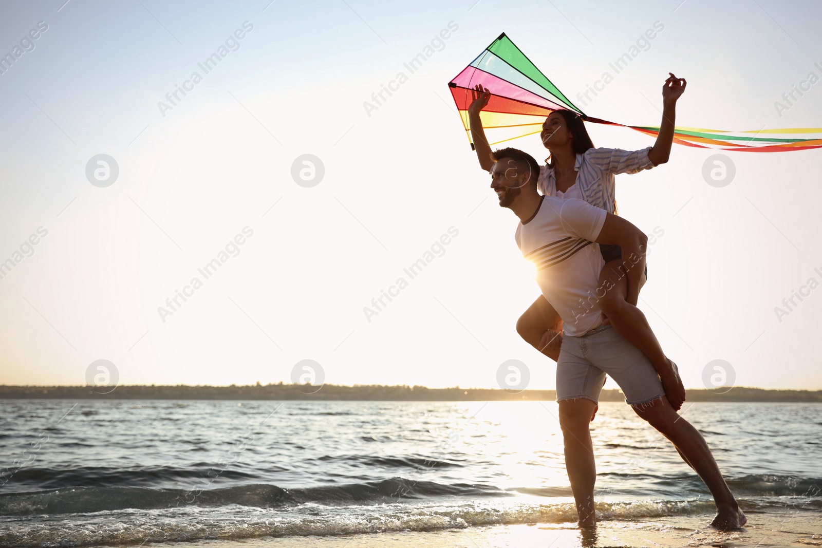 Photo of Happy couple playing with kite on beach near sea. Spending time in nature