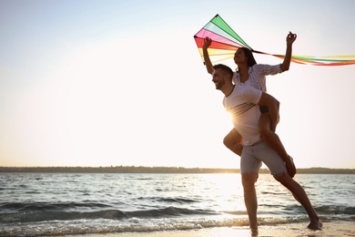 Photo of Happy couple playing with kite on beach near sea. Spending time in nature