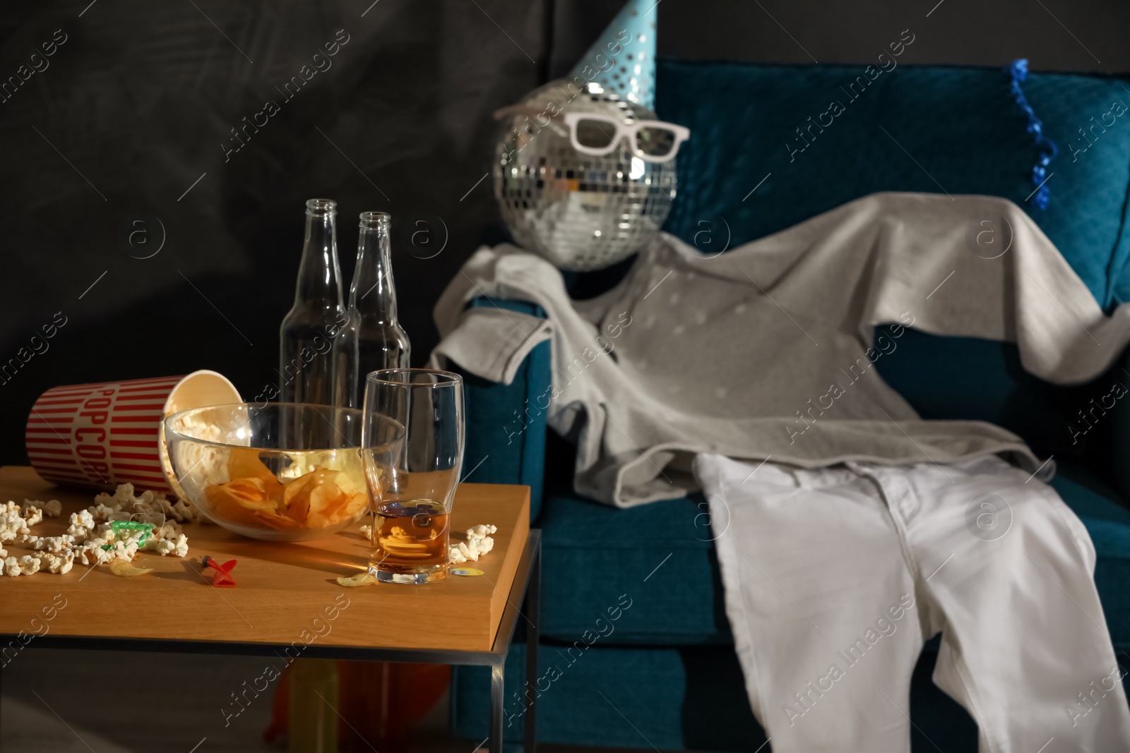 Photo of Messy table with food leftovers near clothes on armchair in room after party