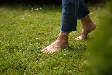 Woman walking barefoot on green grass outdoors, closeup