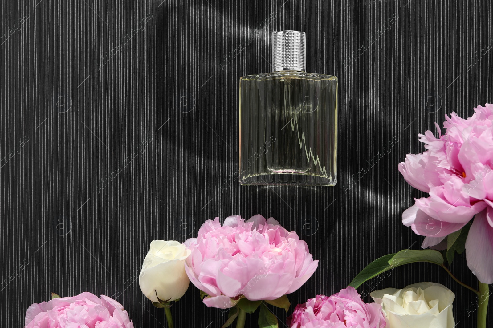 Photo of Luxury perfume and floral decor on dark background, flat lay. Space for text
