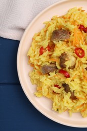Photo of Delicious pilaf with meat on blue wooden table, top view