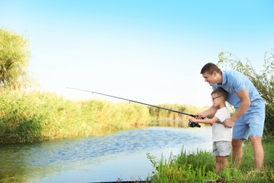 Photo of Dad and son fishing together on sunny day