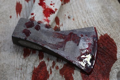 Photo of Axe with blood on wooden surface, closeup