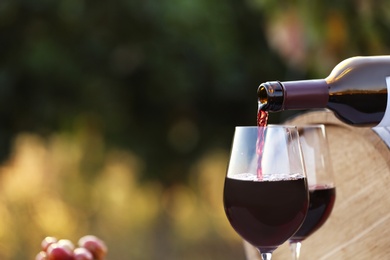 Photo of Pouring wine from bottle into glass outdoors, closeup