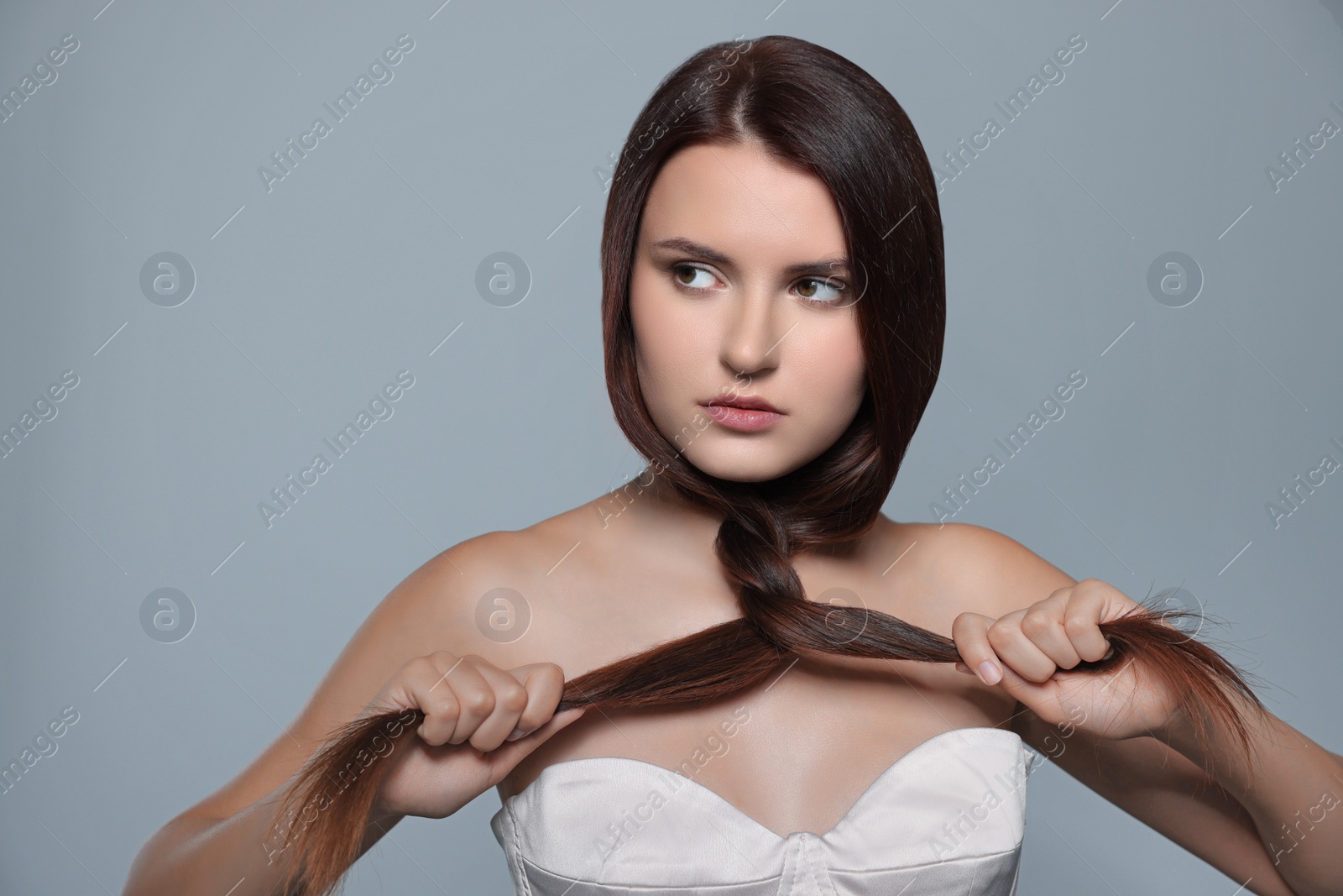 Photo of Portrait of beautiful young woman with healthy strong hair on light gray background